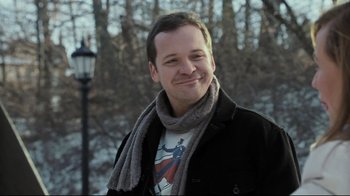 Movie still from “Orphan” (2009), directed by Jaume Collet-Serra – A man wearing a jacket and a scarf smiling for the camera; Close Up shot, Over the shoulder angle
