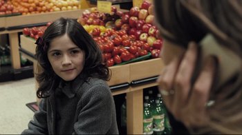 Movie still from “Orphan” (2009), directed by Jaume Collet-Serra – A young girl sitting in front of a display of apples; Close Up shot, Over the shoulder angle