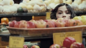 Movie still from “Orphan” (2009), directed by Jaume Collet-Serra – A young girl looking over an abundance of apples in a grocery store; Close Up shot, Over the shoulder angle
