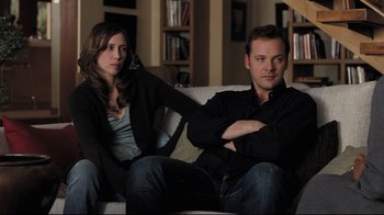 Movie still from “Orphan” (2009), directed by Jaume Collet-Serra – A man and a woman sitting on a couch in a living room; Medium shot, Over the shoulder angle