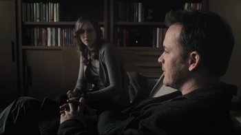 Movie still from “Orphan” (2009), directed by Jaume Collet-Serra – A man and a woman sitting on a couch in front of a book shelf; Medium shot, Over the shoulder angle