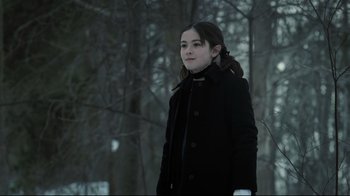 Movie still from “Orphan” (2009), directed by Jaume Collet-Serra – A girl in a black coat standing in the snow; Medium shot, Over the shoulder angle