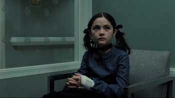 Movie still from “Orphan” (2009), directed by Jaume Collet-Serra – A young girl sitting in a chair with a bandage on her arm; Medium shot, Low angle