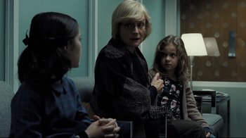 Movie still from “Orphan” (2009), directed by Jaume Collet-Serra – A woman and two young girls sitting in a room; Medium shot, Over the shoulder angle