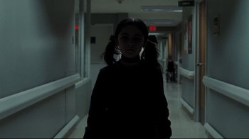 Movie still from “Orphan” (2009), directed by Jaume Collet-Serra – A girl with pigtails standing in a dark hallway; Medium shot, Over the shoulder angle