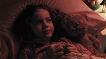 Movie still from “Orphan” (2009), directed by Jaume Collet-Serra – A little girl laying in bed with a teddy bear; Close Up shot, High angle