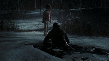 Movie still from “Orphan” (2009), directed by Jaume Collet-Serra – Two people are standing in the snow next to a puddle; Wide shot, High angle