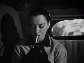 Movie still from “Orpheus” (1950), directed by Jean Cocteau – A woman smoking a cigarette while sitting in the back of a car; Close Up shot, Low angle