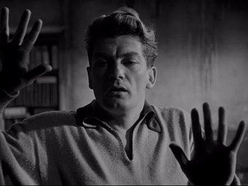 Movie still from “Orpheus” (1950), directed by Jean Cocteau – A black - and - white photo of a man with his hand raised; Close Up shot, Low angle