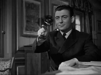 Movie still from “Orpheus” (1950), directed by Jean Cocteau – A black and white photo of a man in a suit and tie; Medium shot, Low angle