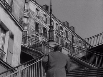 Movie still from “Orpheus” (1950), directed by Jean Cocteau – A black and white photo of a man walking up a set of stairs; Wide shot, Low angle