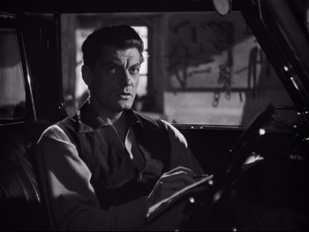 Movie still from “Orpheus” (1950), directed by Jean Cocteau – A black and white photo of a man driving a car; Medium shot, Over the shoulder angle