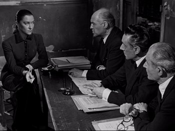 Movie still from “Orpheus” (1950), directed by Jean Cocteau – A black and white photo of people sitting at a table; Medium shot, Over the shoulder angle
