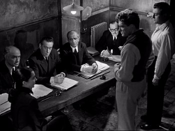 Movie still from “Orpheus” (1950), directed by Jean Cocteau – A black and white photo of people sitting at a table; Wide shot, Over the shoulder angle