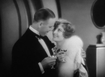 Movie still from “Our Dancing Daughters” (1928), directed by Harry Beaumont – A man and a woman are holding wine glasses; Medium shot, High angle