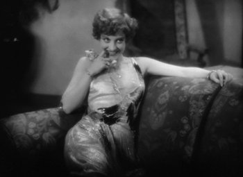 Movie still from “Our Dancing Daughters” (1928), directed by Harry Beaumont – An old photo of a woman sitting on a couch; Medium shot, High angle