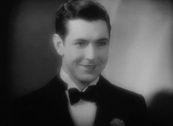 Movie still from “Our Dancing Daughters” (1928), directed by Harry Beaumont – An old photo of a man in a suit and bow tie; Close Up shot, High angle