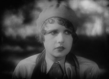 Movie still from “Our Dancing Daughters” (1928), directed by Harry Beaumont – An old photo of a woman wearing a hat and tie; Close Up shot, High angle
