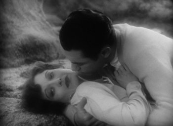 Movie still from “Our Dancing Daughters” (1928), directed by Harry Beaumont – A man and a woman laying on the ground kissing; Medium shot, Overhead angle