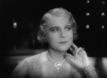 Movie still from “Our Dancing Daughters” (1928), directed by Harry Beaumont – An old photo of a woman in a dress and a pearl necklace; Close Up shot, High angle