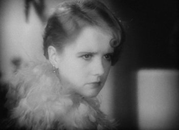 Movie still from “Our Dancing Daughters” (1928), directed by Harry Beaumont – A black - and - white photo of a young woman wearing a feather boa; Close Up shot, High angle