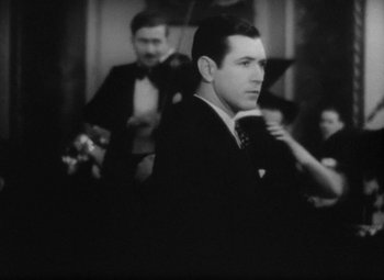Movie still from “Our Dancing Daughters” (1928), directed by Harry Beaumont – A black and white photo of a man in a suit and bow tie; Close Up shot, Over the shoulder angle