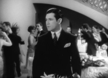 Movie still from “Our Dancing Daughters” (1928), directed by Harry Beaumont – A black and white photo of a man in a suit and tie; Medium shot, High angle