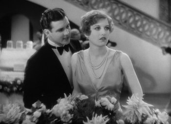 Movie still from “Our Dancing Daughters” (1928), directed by Harry Beaumont – A man standing next to a woman holding a bouquet of flowers; Medium shot, Low angle