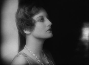Movie still from “Our Dancing Daughters” (1928), directed by Harry Beaumont – An old photo of a woman with a pearl necklace; Close Up shot, Low angle