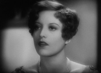 Movie still from “Our Dancing Daughters” (1928), directed by Harry Beaumont – An old photo of a woman in a dress and pearls; Close Up shot, High angle
