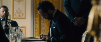 Movie still from “Our Kind of Traitor” (2016), directed by Susanna White – A man writing on a piece of paper; Medium shot, Over the shoulder angle