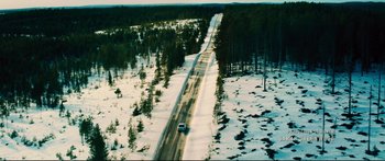 Movie still from “Our Kind of Traitor” (2016), directed by Susanna White – An aerial view of a car driving down a snowy road; Extreme Wide shot, High angle