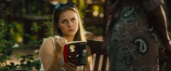 Movie still from “Our Kind of Traitor” (2016), directed by Susanna White – A woman sitting at a table reading a book; Close Up shot, Over the shoulder angle