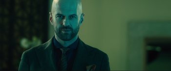 Movie still from “Our Kind of Traitor” (2016), directed by Susanna White – A man with a bald head wearing a suit and tie; Close Up shot, Low angle