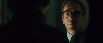 Movie still from “Our Kind of Traitor” (2016), directed by Susanna White – A person wearing glasses and a suit; Close Up shot, Over the shoulder angle