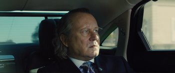 Movie still from “Our Kind of Traitor” (2016), directed by Susanna White – A man in a suit and tie sitting in the back of a car; Close Up shot, Low angle