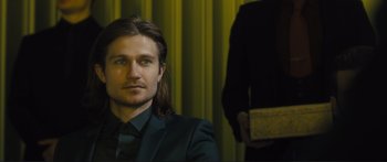 Movie still from “Our Kind of Traitor” (2016), directed by Susanna White – A man with long hair wearing a black suit; Close Up shot, Over the shoulder angle