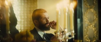 Movie still from “Our Kind of Traitor” (2016), directed by Susanna White – A man with a long beard is brushing his teeth in front of candles; Close Up shot, Low angle