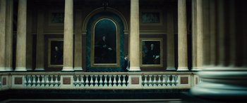 Movie still from “Our Kind of Traitor” (2016), directed by Susanna White – A man standing in front of two paintings on a wall; Extreme Wide shot, Low angle