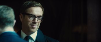 Movie still from “Our Kind of Traitor” (2016), directed by Susanna White – A person wearing glasses and a suit; Close Up shot, Low angle