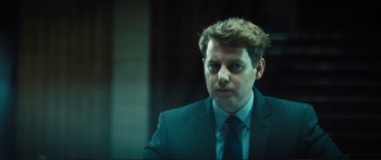 Movie still from “Our Kind of Traitor” (2016), directed by Susanna White – A person wearing a suit and tie; Close Up shot, Over the shoulder angle