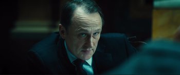 Movie still from “Our Kind of Traitor” (2016), directed by Susanna White – A person wearing a suit and tie; Close Up shot, Over the shoulder angle