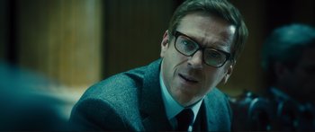 Movie still from “Our Kind of Traitor” (2016), directed by Susanna White – A person wearing a suit and glasses; Close Up shot, Over the shoulder angle
