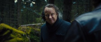 Movie still from “Our Kind of Traitor” (2016), directed by Susanna White – An older man with long hair wearing a black sweater; Close Up shot, Over the shoulder angle