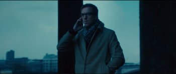 Movie still from “Our Kind of Traitor” (2016), directed by Susanna White – A man in a trench coat is talking on a cell phone; Medium shot, Low angle