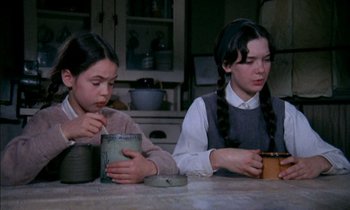 Movie still from “Our Mother's House” (1967), directed by Jack Clayton – Two young girls sitting at a kitchen table drinking from cups; Medium shot, High angle