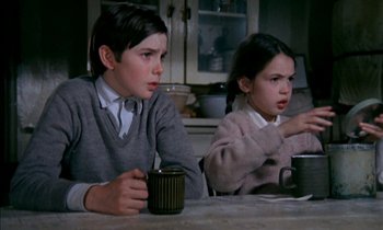 Movie still from “Our Mother's House” (1967), directed by Jack Clayton – Two young children sitting at a table with a cup; Medium shot, Low angle