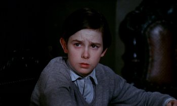 Movie still from “Our Mother's House” (1967), directed by Jack Clayton – A young boy in a sweater and tie looking at the camera; Close Up shot, High angle