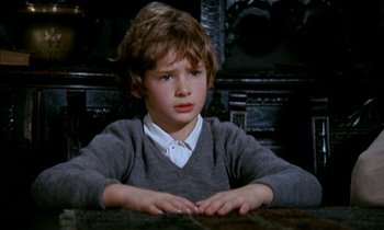 Movie still from “Our Mother's House” (1967), directed by Jack Clayton – A young boy sitting at a table in front of a wall; Medium shot, High angle