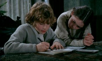 Movie still from “Our Mother's House” (1967), directed by Jack Clayton – Two young children are writing on paper at a table; Medium shot, High angle